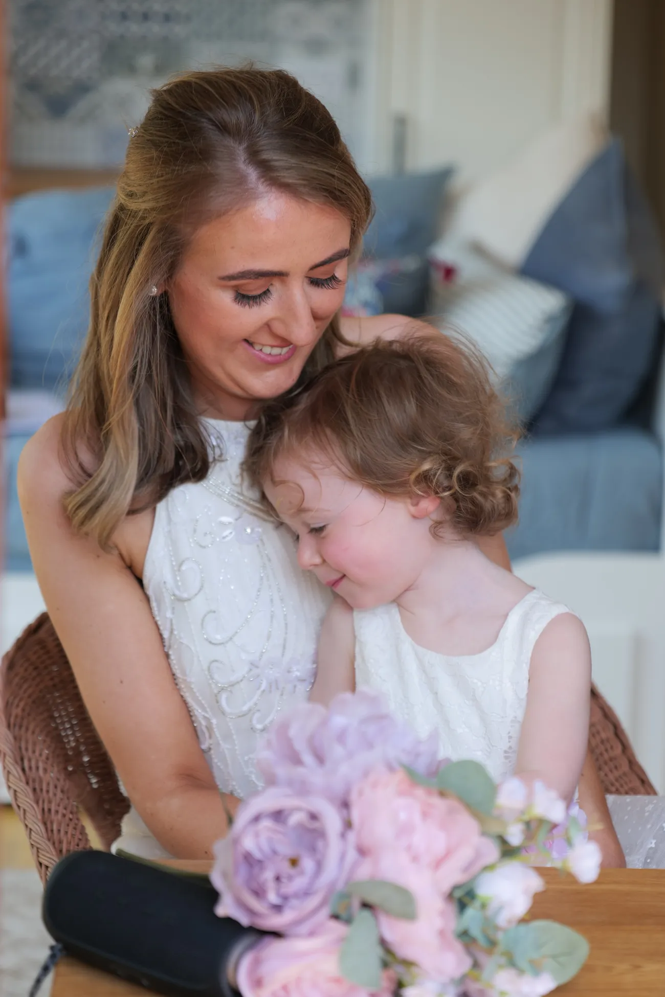 Bride cuddling a flower girl with a lilac bouquet