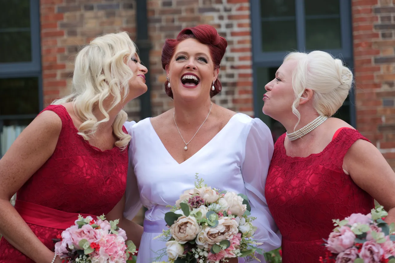 Bride laughing with bridesmaids in red dresses