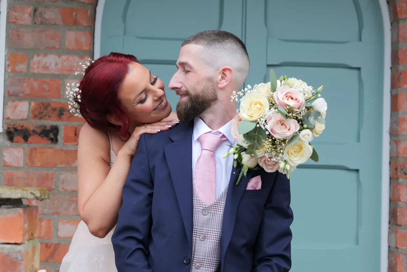 Wedding portrait by a doorway with bouquet held up