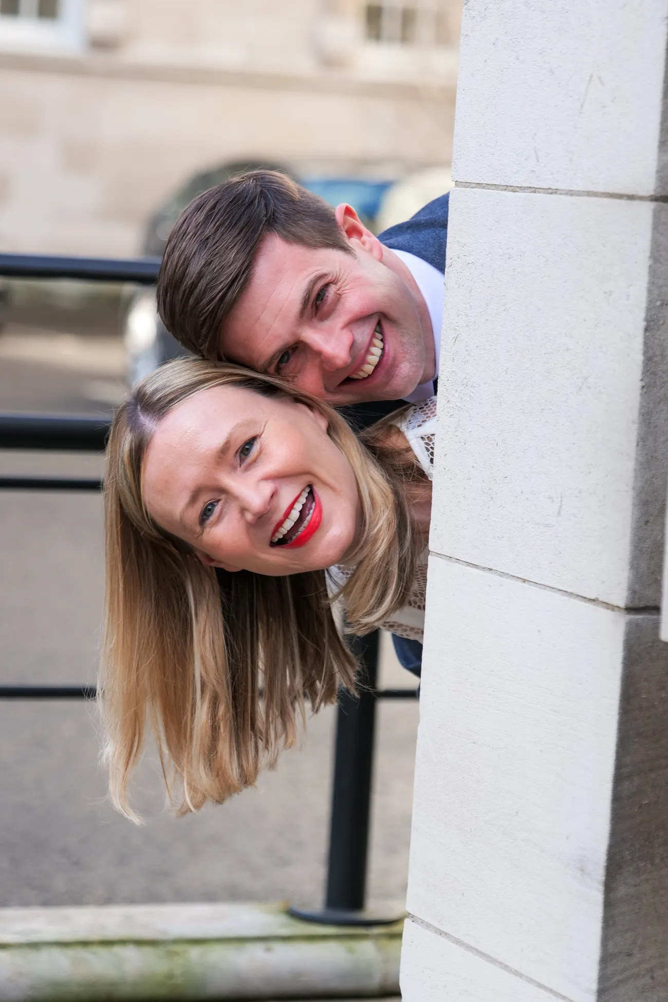 Playful couple peeking around a stone column
