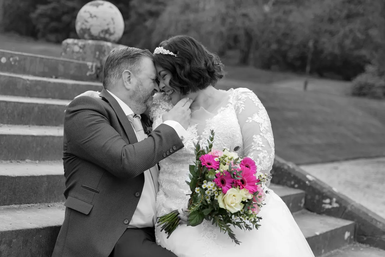 Wedding kiss on outdoor stairs with a bright pink bouquet