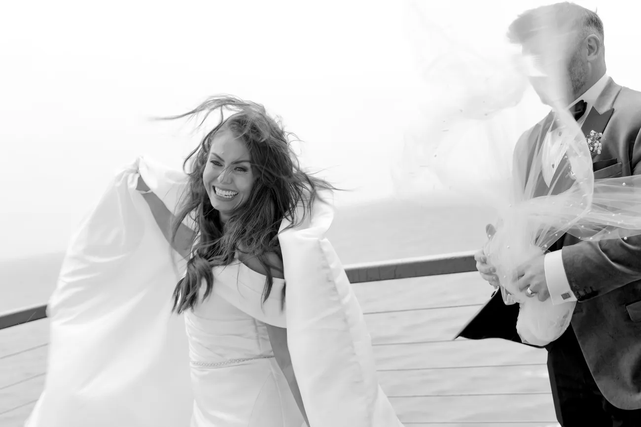 Windblown bride and groom on a deck in black and white