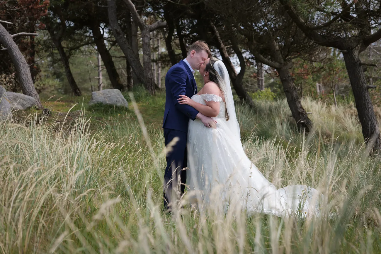 Wedding portrait among tall grass at woodland edge